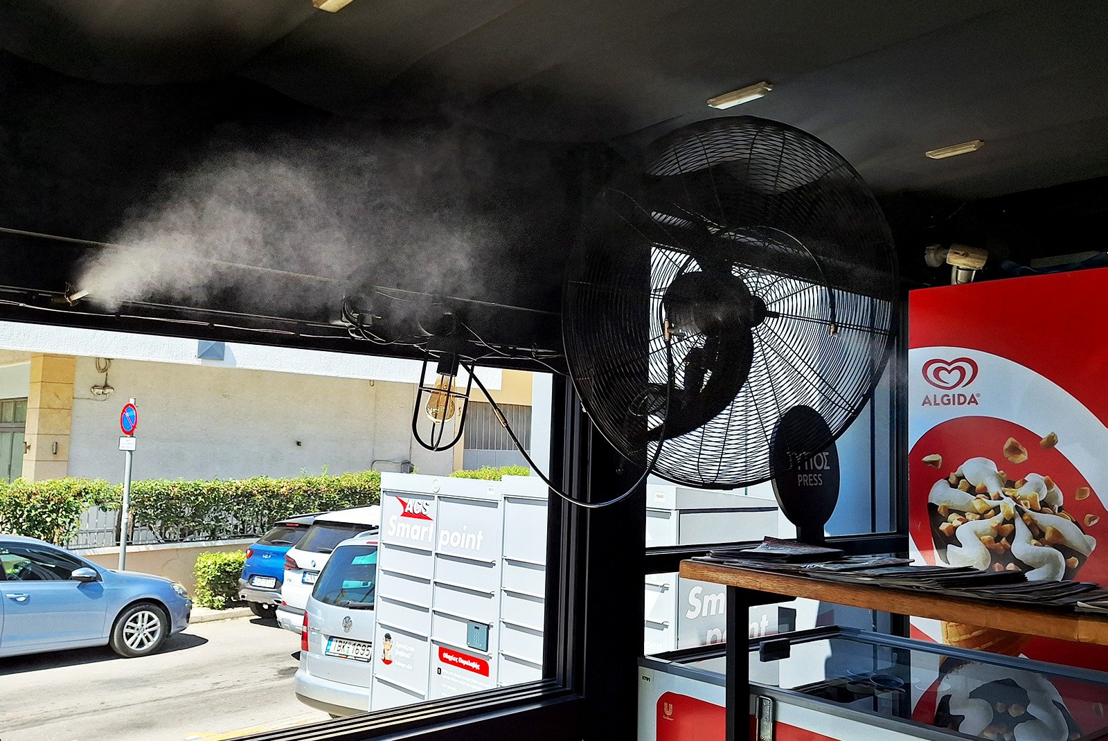 Επαγγελματικά ακροφύσια και ανεμιστήρας υδρονέφωσης Technomist Misting Systems σε καφετέρια, μίνι μάρκετ